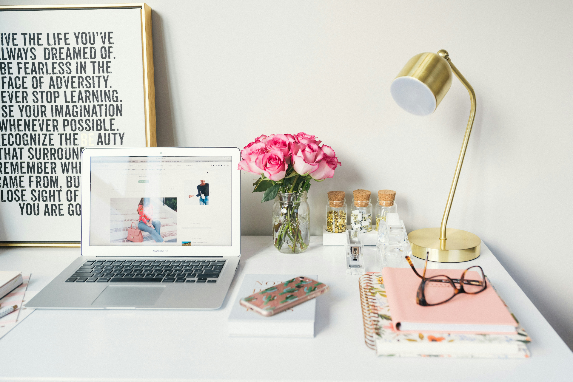 A light-filled workspace with a laptop, notebooks, and flowers